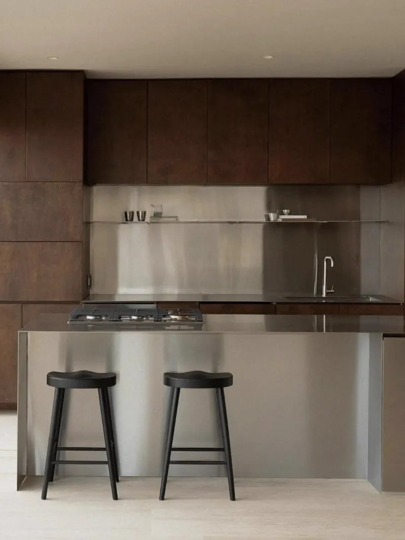 Cuisine en bois foncé et inox, îlot central et tabourets noirs