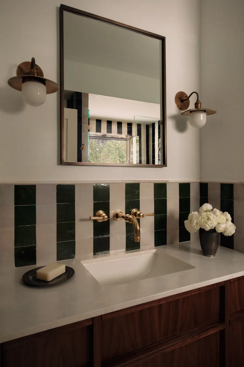 Salle de bain : vasque blanche, robinetterie laiton et carrelage vert et blanc